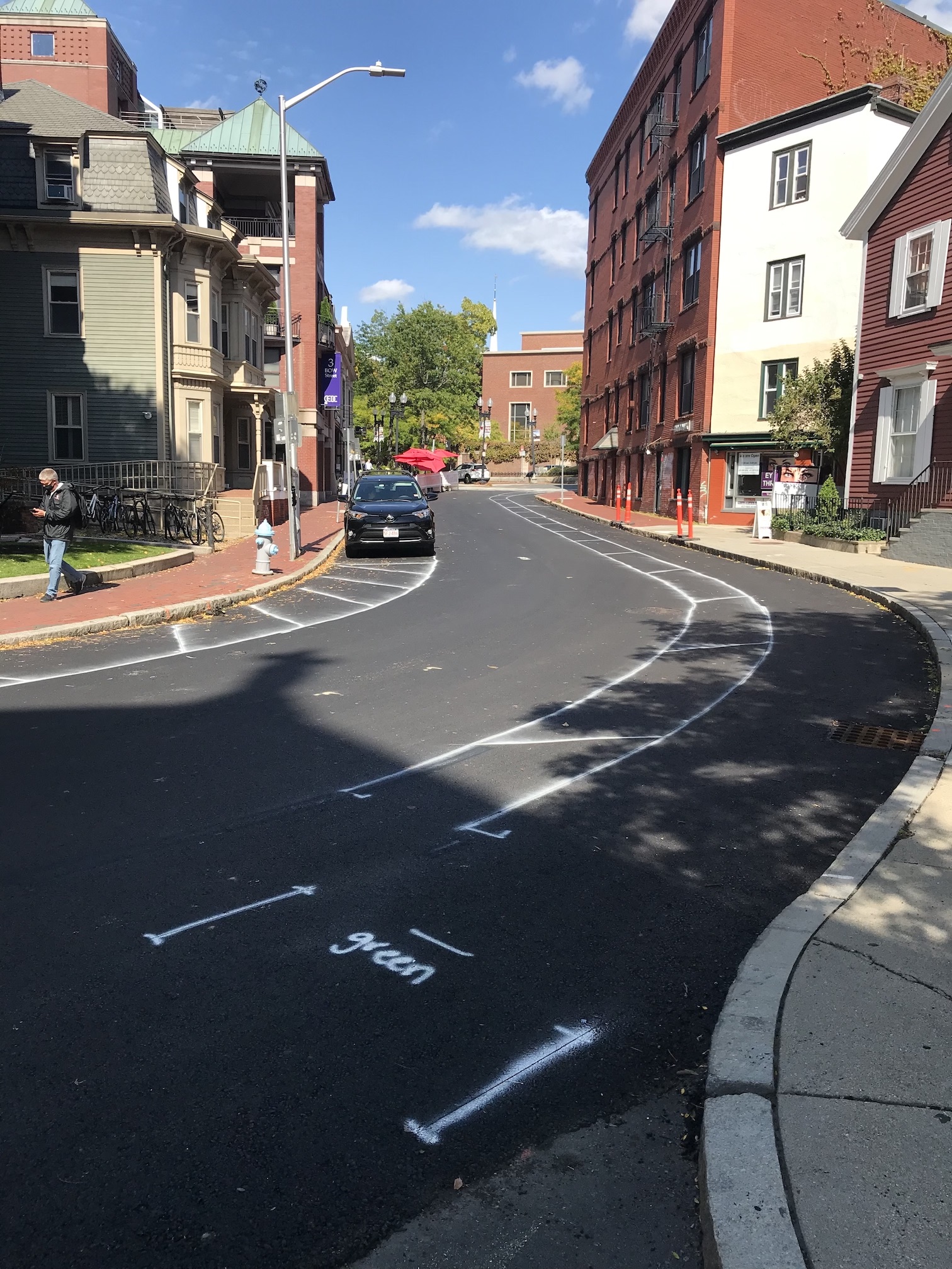 Preliminary pavement markings on Bow Street show the location of a new contraflow bike lane, which will be buffered from southbound motor vehicle traffic with flexible post bollards.