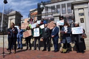Becca Wolfson, Executive Director of the Boston Cyclists Union, speaks in front of a crowd of supporters holding signs in support of e-bike legislation in front of the Massachusetts State House.