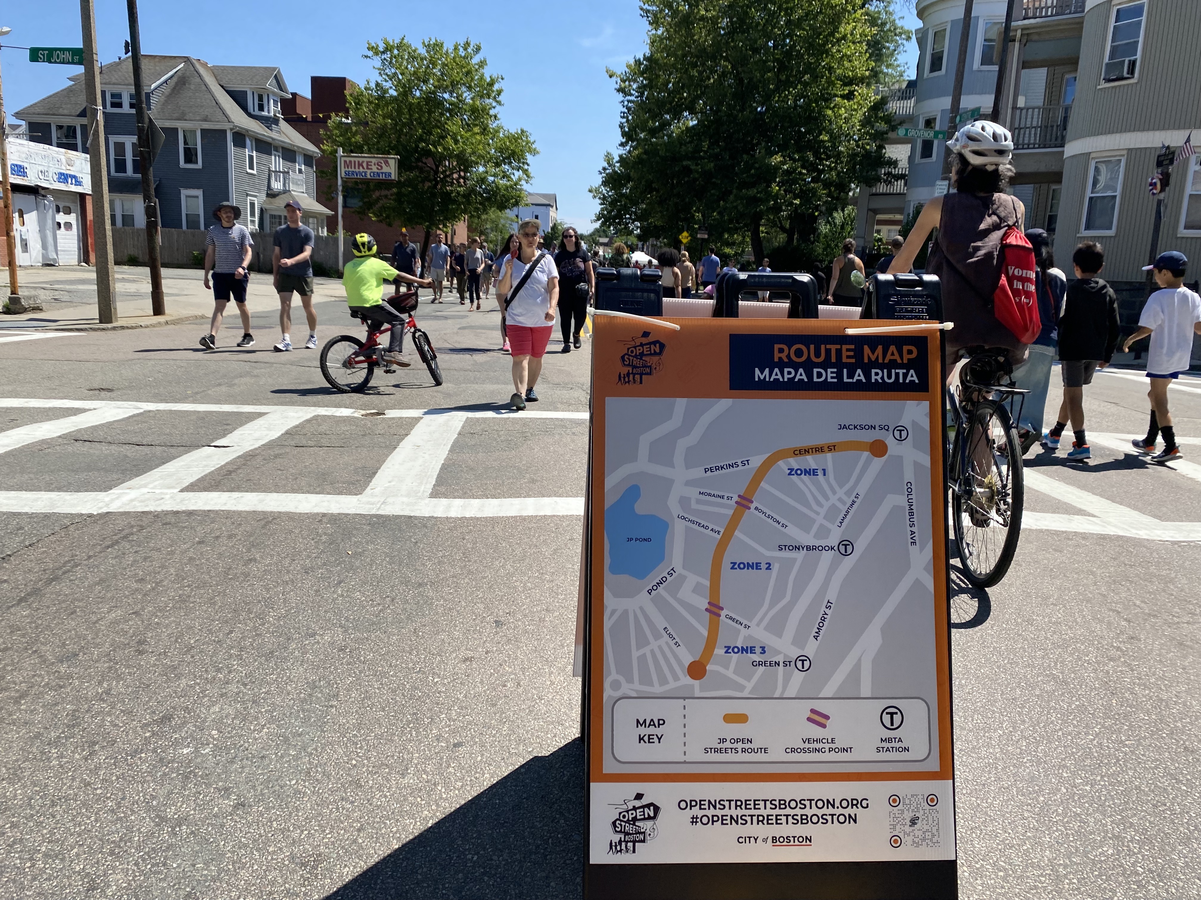 Crowds walk and roll past a map of Sunday's Open Streets event in Jamaica Plain.