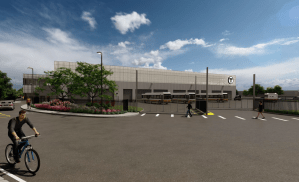 A rendering of a new bus garage, showing a gray, low-slung building with eight garage doors facing the viewer, and three black-and-yellow MBTA buses parked in the lot in front. In the foreground, a bike rider and two pedestrians walk along the garage driveway. The MBTA's "T" logo is visible on the top of the building.