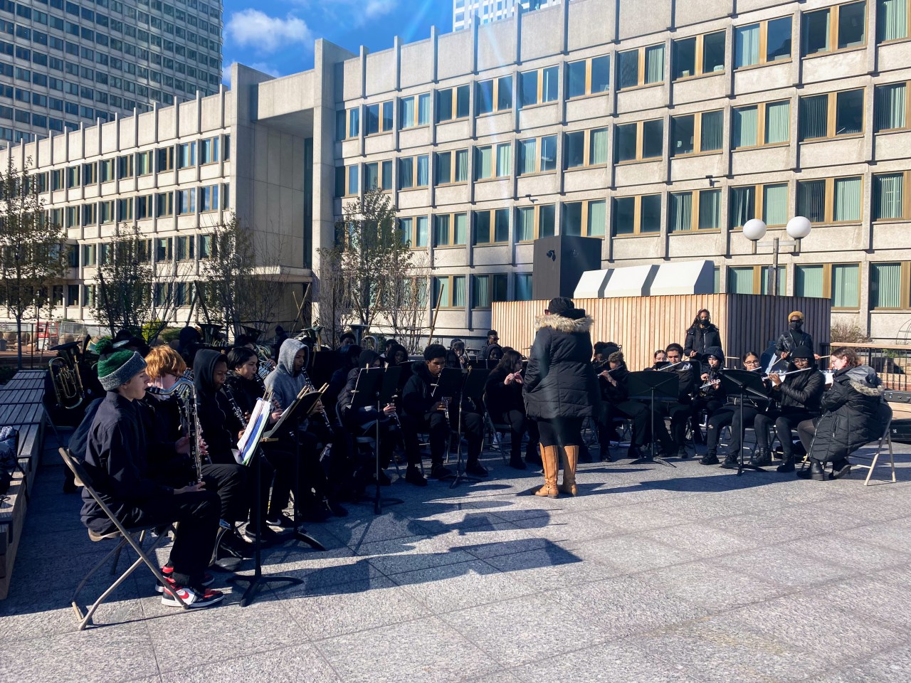 students dressed in black sit while they play their instruments on the rooftop terrace of the new Civic Pavillion at City Hall Plaza.