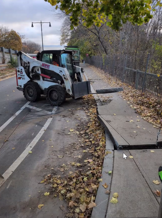 Staff operating a forklift to restructure sidewalk.