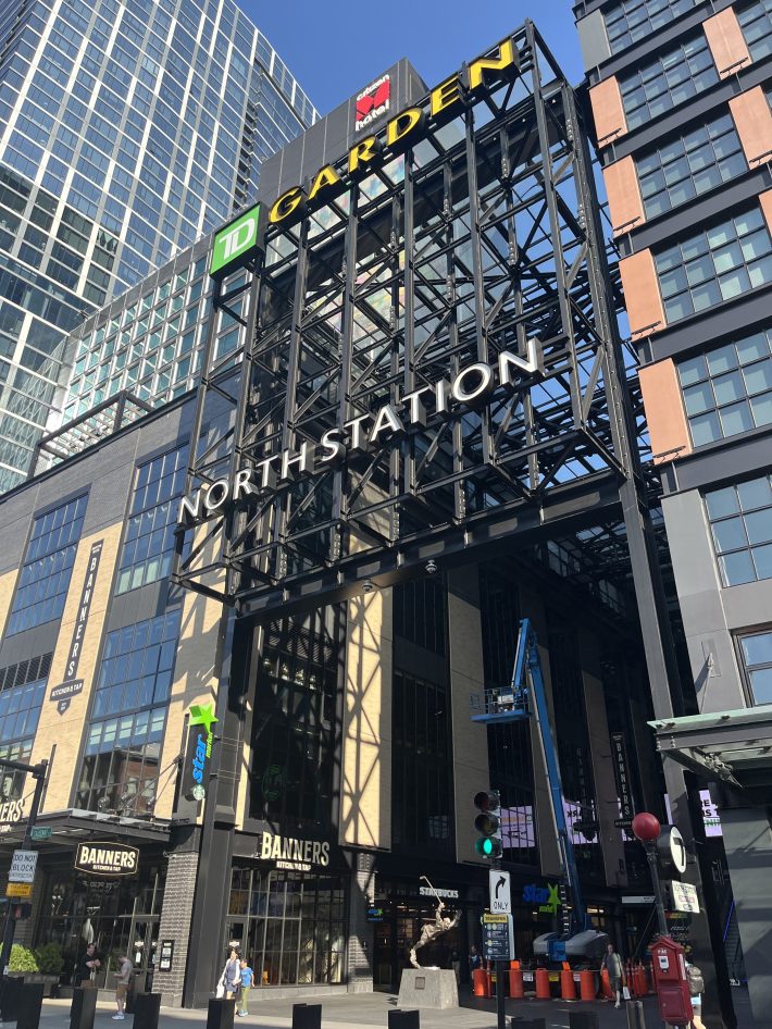 The North Station entrance on Causeway Street underneath a sign for TD Garden, bookended by tall buildings and busy storefronts.