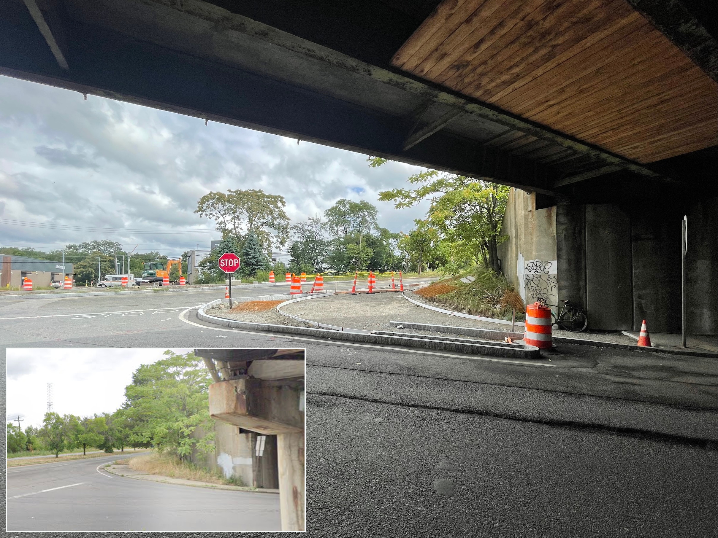 A highway construction site under a highway overpass which looms in shadow over the top edge of the photo. New granite curbs have been installed in the middle of an older roadway in the center of the photo, curving at a road junction. An inset at lower left shows what the same scene looked like before construction, when there was a much narrower sidewalk at the corner.
