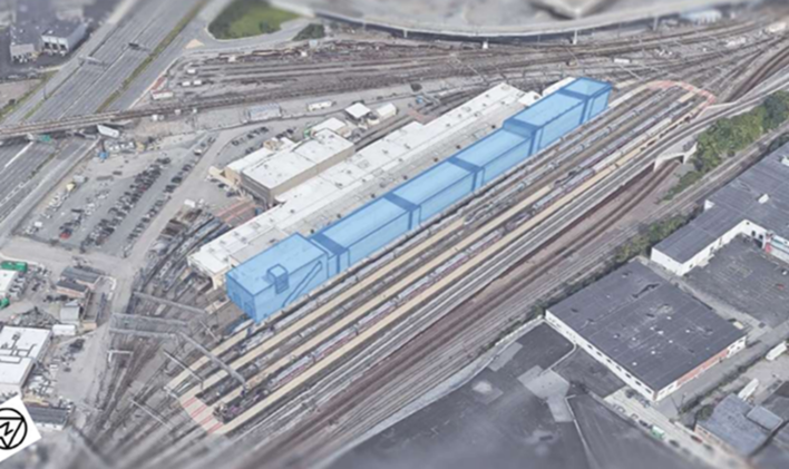 An aerial view of a train yard with a drawing of a large warehouse over two tracks superimposed in blue