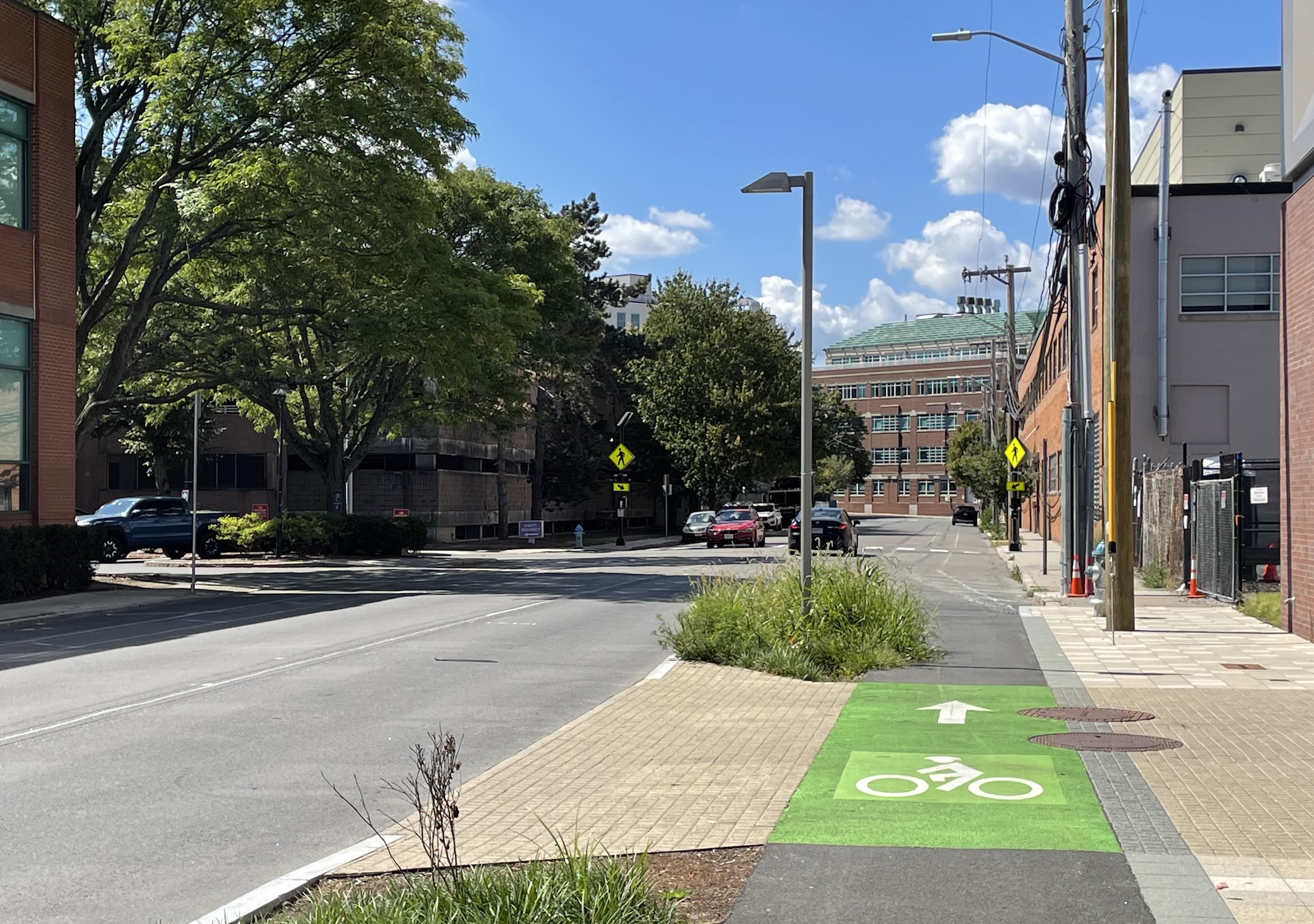 A sidewalk-level protected bike lane, which ends in the middle distance and merges into the street. 