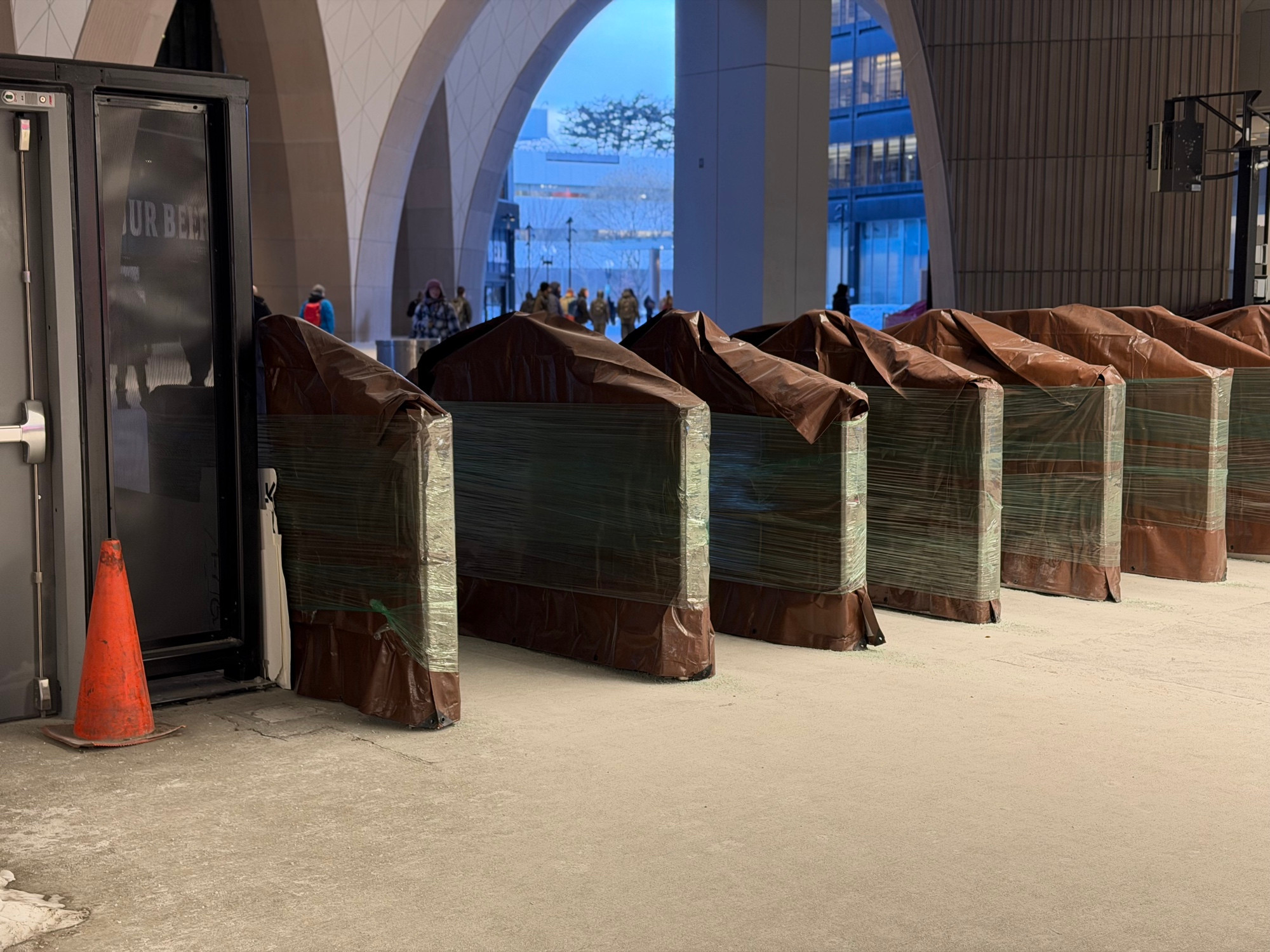 A row of columns wrapped in black plastic under the high arches of a train hall.