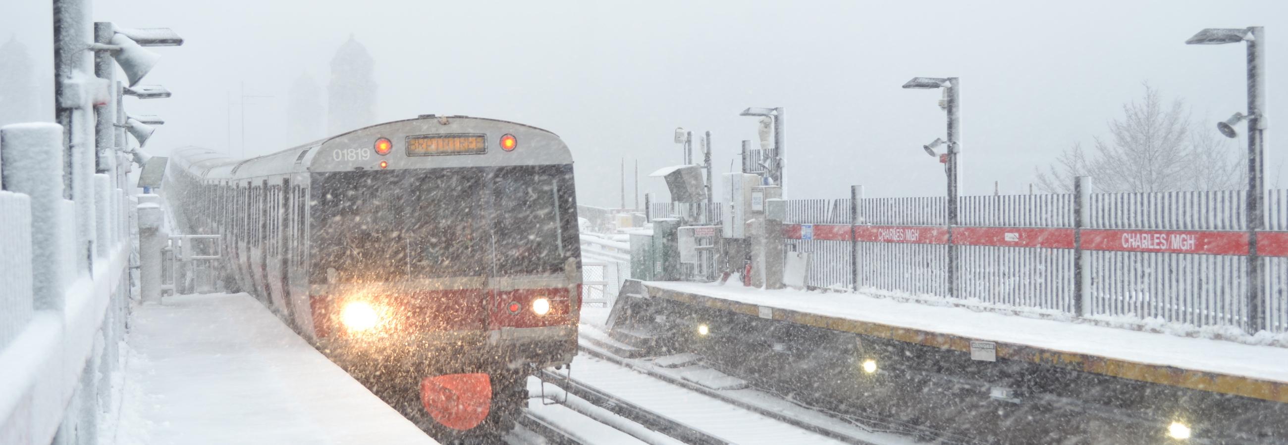 A Red Line train arrives at the Charles/MGH outdoor station platform in a heavy snowstorm.