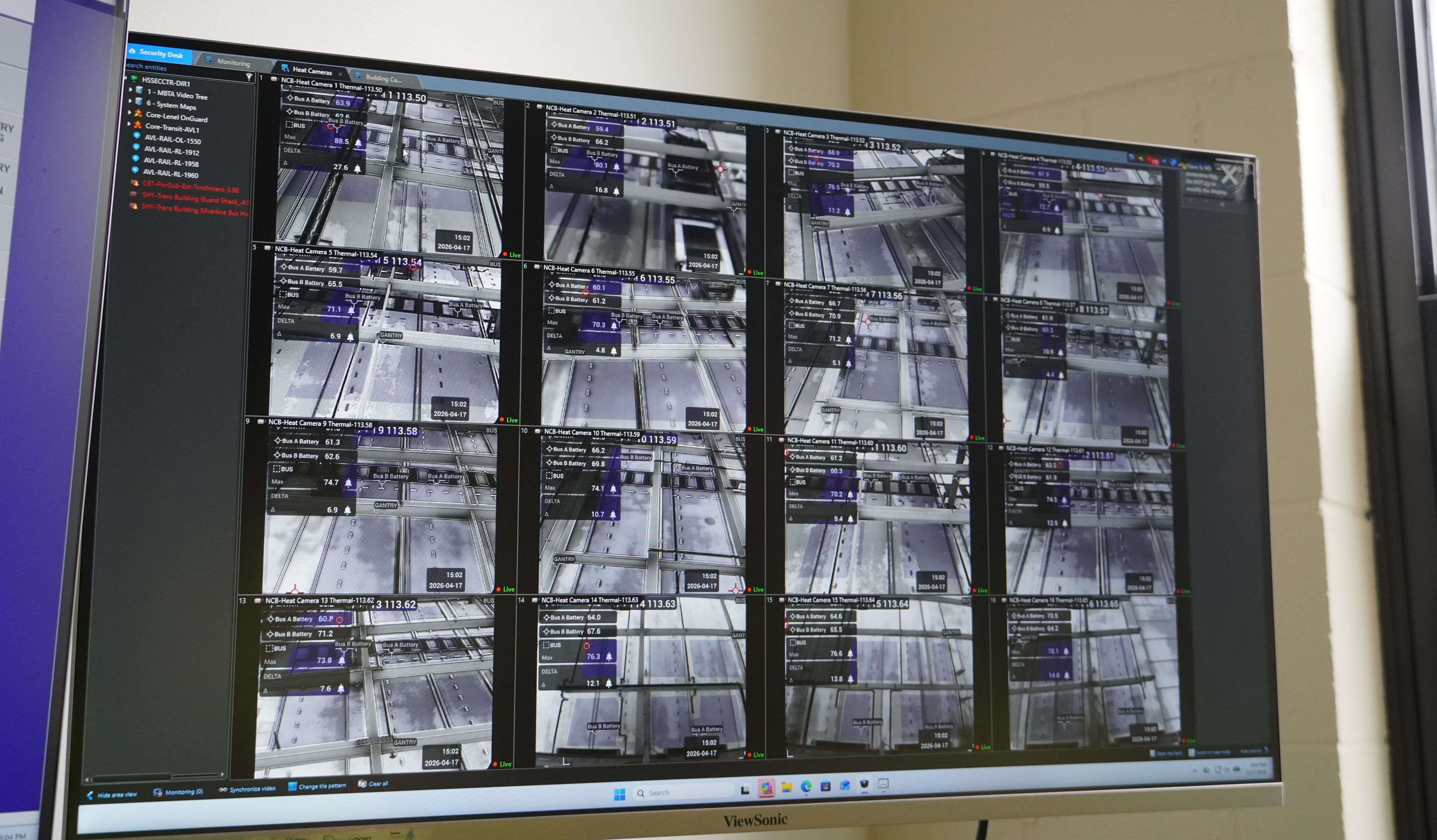 A 4X4 grid of black-and-white surveillance videos showing the charging bays of a bus garage on a computer screen.