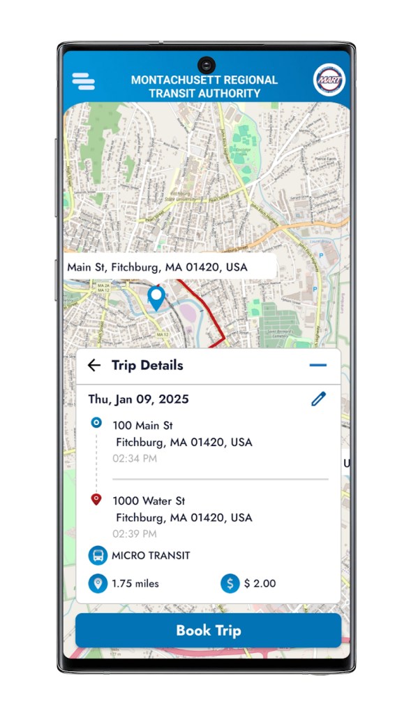 A smartphone screen shows the mobile app interface for the Montachusett Regional Transit Authority's MART Connects app. The screen shows the MART logo, agency name, and a map depicting a route in Fitchburg, Massachusetts, with a pin dropped near Main Street. A "Trip Details" card is shown on the lower half of the screen, showing a scheduled microtransit trip for Thursday, January 09, 2025 departing from 100 Main St at 2:34 PM and arriving at 1000 Water St at 2:39 PM, specifying a "Micro Transit" service type, a distance of 1.75 miles, and a cost of $2.00. A blue "Book Trip" button sits at the bottom of the screen.