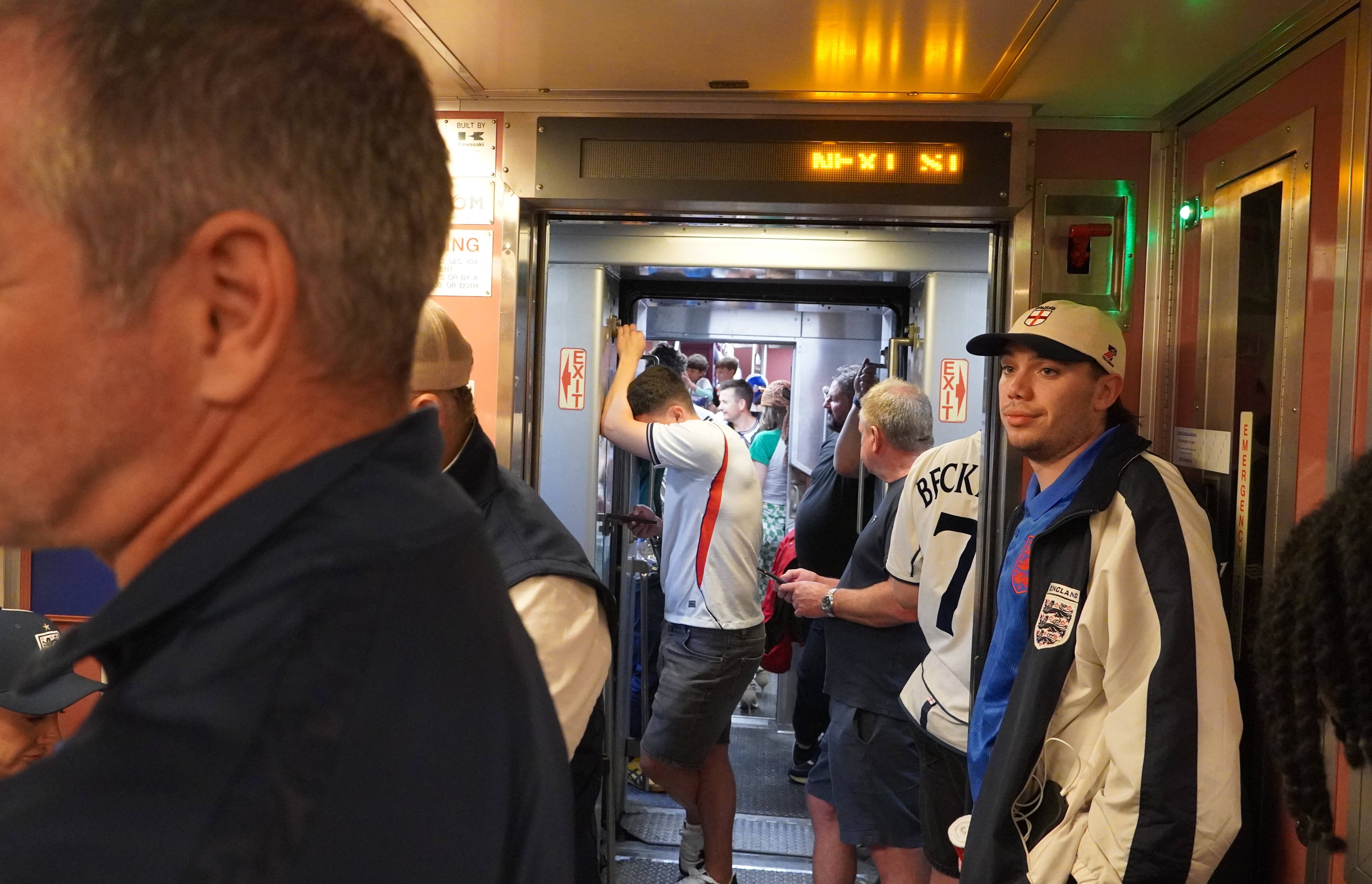 Men wearing soccer jerseys crowd a standing-room-only train car.