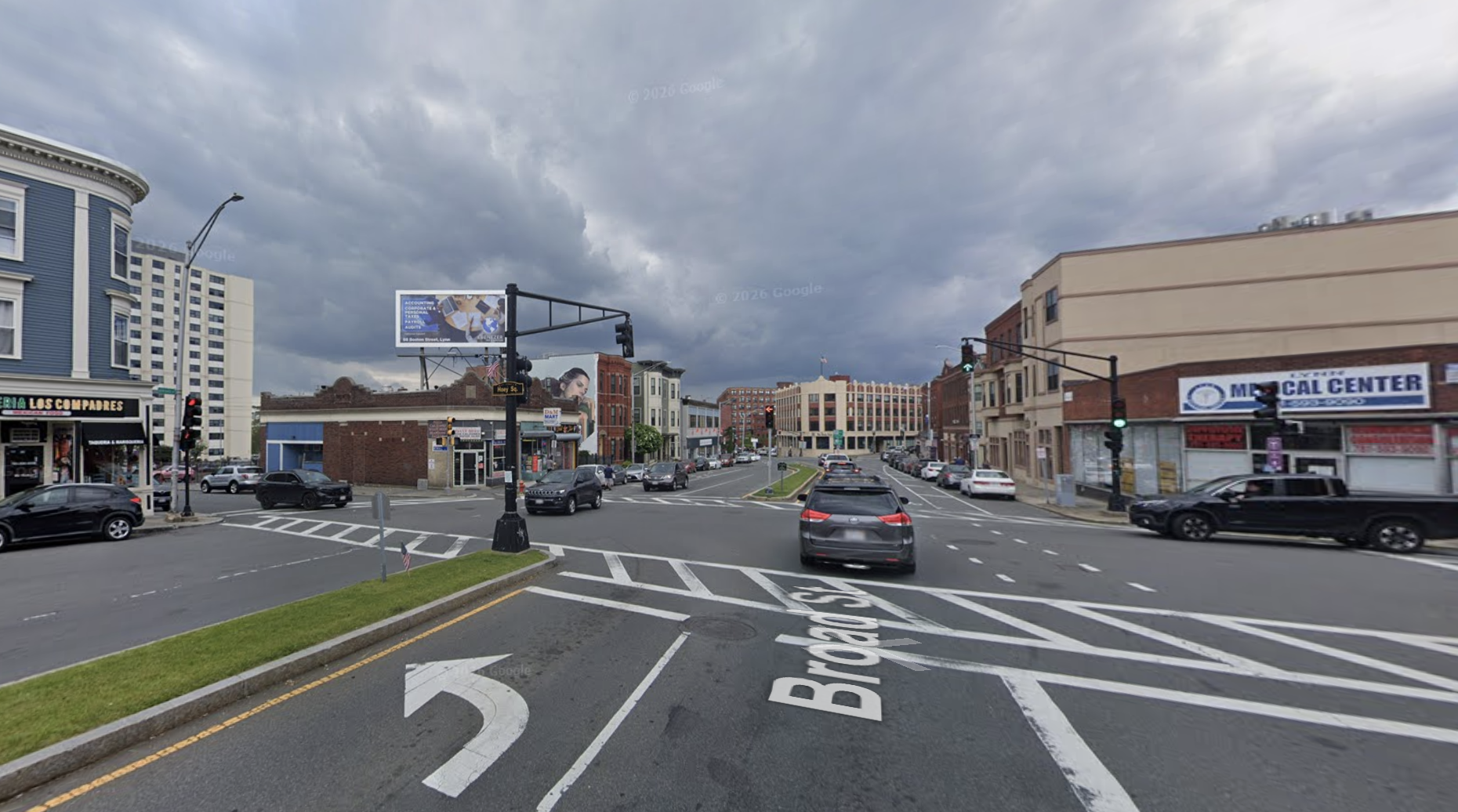 A wide intersection surrounded by older brick and masonry multi-story buildings.