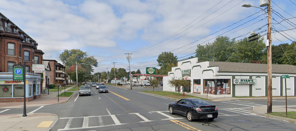 A Google Street View of a four-lane street lined with 1- to 3-story commercial buildings against the sidewalk.